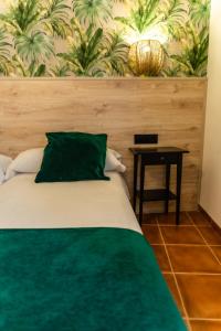 a bed with a green pillow and a table at Hostal El Bomba 