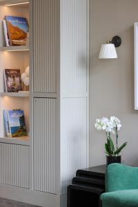 ein Bücherregal in einem Wohnzimmer mit einem grünen Stuhl in der Unterkunft Mimosa Hotel in Westerland + 77 Fotos