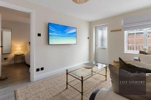 a living room with a couch and a tv on the wall at 11 Friernhay Court in Exeter