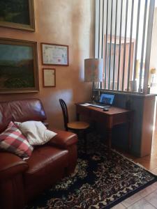 sala de estar con sofá y escritorio con ordenador portátil en Casa vacanza L'arte di Ba' - Maison, en San Nicola Arcella