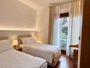 Habitación de hotel con 2 camas y ventana en Villa Phoenix - Lake Apartments, en Riva del Garda