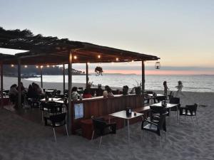 personas sentadas en un bar en la playa en Playa, Jardín y piscina en Cabo Udra en Pontevedra