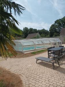 a picnic table and a bench in front of a greenhouse at La Maison de Zoé in Saint-Denis-sur-Loire