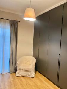 une chaise blanche assise dans une pièce avec fenêtre dans l'établissement Eleusis luxury flat, à Elefsina