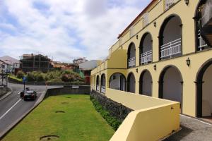 a yellow building with grass next to a street at Vinha da Areia Beach Hotel in Vila Franca do Campo