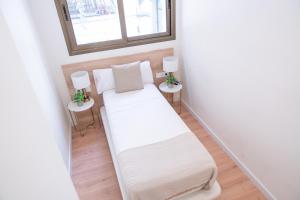 een kleine kamer met een bed en twee tafels bij Rambla de Mar Apartments in Barcelona