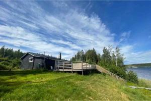 a building on the side of a field with a body of water at 3 bedroom lakehouse with private bridge and garden in Sundsvall