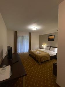 a hotel room with two beds and a desk at Pensiunea Perla Codrului 