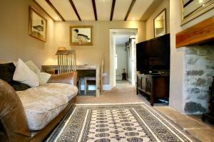 a living room with a couch and a television at Holmlea Cottage in Mickleton