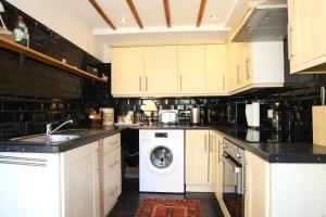 a kitchen with white cabinets and a washing machine at Holmlea Cottage in Mickleton