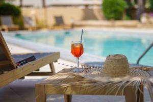 un sombrero de paja y una bebida sentado en una mesa junto a una piscina en Apartaments Andreas en Colonia Sant Jordi
