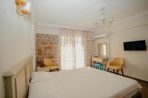 sypialnia z łóżkiem, krzesłami i telewizorem w obiekcie Yakamoz Hotel Gökçeada w mieście Gokceada