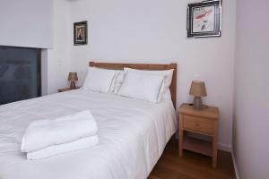 a white bed with white pillows and a night stand at Porto Sunset suite in Vila Nova de Gaia
