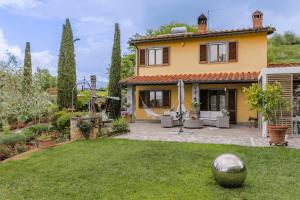 a yellow house with a yard with a ball in the yard at Villa Lolù in Terranuova Bracciolini