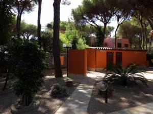 een oranje gebouw met bomen en planten in een tuin bij Le Due Tortore Home Holiday - Villa con splendido giardino ad un minuto a piedi dal mare in Fort Village