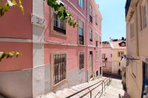 um beco numa cidade velha com edifícios cor-de-rosa em Historical Apartment em Lisboa