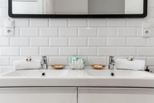 een witte wastafel met twee kranen en een spiegel bij Happy Stay Sopot Monte Cassino 44 B in Sopot