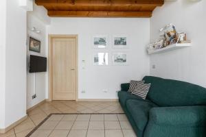 a living room with a green couch and a door at Osvaldo - parcheggio e giardino privato in San Giovanni in Persiceto