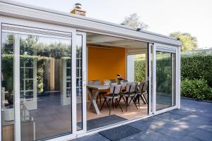 een uitbreiding van een serre met een tafel en stoelen bij Familie bungalow op vakantiepark bij zee in Baarland