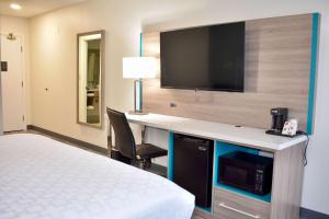 a hotel room with a bed and a desk with a tv at Clarion Pointe Vidalia - Lyons West in Vidalia