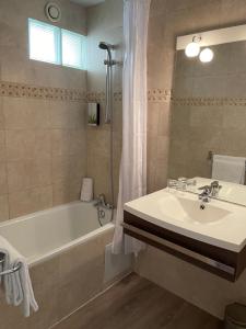 a bathroom with a tub and a sink and a bath tub at Hôtel Le Médiéval Palais des Papes in Avignon