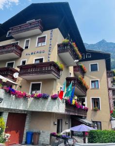 a building with flower boxes and flags on it at Hotel Genzianella in Chiesa in Valmalenco