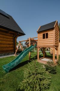 a playground with a slide and a wooden house at Domek drewniany - Czerwienne in Czerwienne