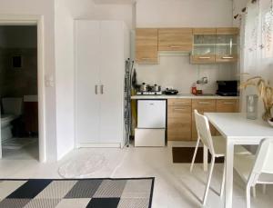 a white kitchen with a table and a refrigerator at Maggie’s Art Studio in Mesongi