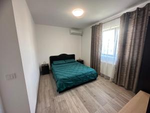 - une chambre avec un lit vert et une fenêtre dans l'établissement Apartament Elena, à Bragadiru
