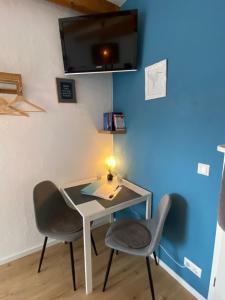 a table and two chairs in a room with a blue wall at Kleines Doppelzimmer mit eigenem Bad und Kühlschrank, frisch saniert in Friedrichskoog