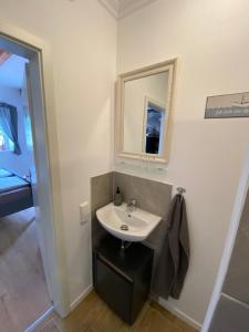 La salle de bains est pourvue d'un lavabo et d'un miroir. dans l'établissement Kleines Doppelzimmer mit eigenem Bad und Kühlschrank, frisch saniert, à Friedrichskoog
