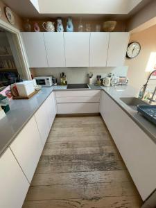 a kitchen with white cabinets and a wooden floor at Beautiful Family-Friendly 4BD House - North Sheen in Kew Gardens