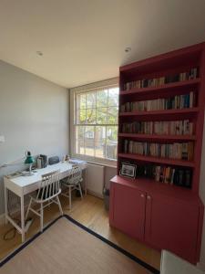 a room with a desk and a book shelf with books at Beautiful Family-Friendly 4BD House - North Sheen in Kew Gardens