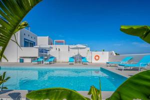 een zwembad met blauwe stoelen en een gebouw bij Xenos Villa 6 with a Private pool near the sea in Tigaki