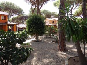 a garden with trees and bushes and buildings at Le Due Tortore Home Holiday - Villa con splendido giardino ad un minuto a piedi dal mare in Forte Village