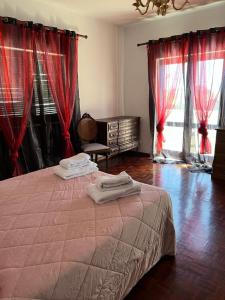 een slaapkamer met een bed met rode gordijnen bij Vivenda Marias in Lagoa