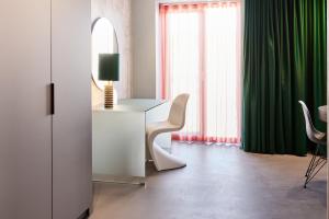 Habitación con mesa, espejo y cortinas verdes. en Kirk Suites, en Vejle