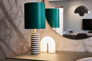 a lamp on top of a table with a mirror at Kirk Suites in Vejle