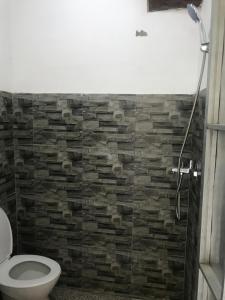 uma casa de banho com um WC e uma parede de tijolos em Makini Guest House em Lambangkuning