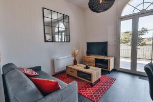 ein Wohnzimmer mit einem Sofa und einem Flachbild-TV in der Unterkunft Domaine Grand Piquecaillou - L'appartement Sainte-Croix-Du-Monts 