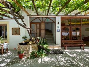 a building with a porch with a bench and a tree at Lefka in Kolymvari