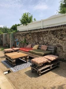 patio con sofá, mesas y pared de piedra en Maison de famille, en Saint-Mars-dʼOutillé
