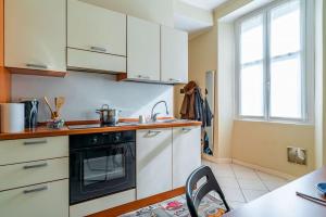 uma cozinha com armários brancos e um forno preto em River Apartment - Affitti Brevi Italia em Lecco