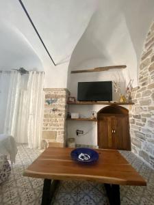 ein Wohnzimmer mit einem Tisch und einem TV in der Unterkunft Cozy stone built apartment in Nénita! in Chios