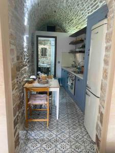 cocina con mesa y nevera en Cozy stone built apartment in Nénita!, en Chios