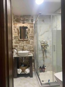 y baño con ducha acristalada y lavamanos. en Cozy stone built apartment in Nénita!, en Chios