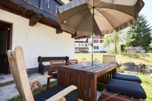 une table et des chaises en bois avec un parasol dans l'établissement Ferienwohnung Hubert, à Rottach-Egern