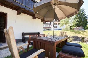un tavolo in legno con sedie e ombrellone di Ferienwohnung Hubert a Rottach-Egern
