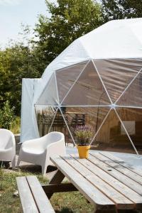 Tienda de campaña con mesa de madera, sillas y mesa de picnic con una planta en Glamping Dome Tent en Jubbega-Schurega
