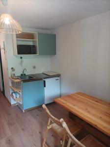 uma cozinha com uma mesa de madeira e um frigorífico azul em Studio Morillon Village em Morillon